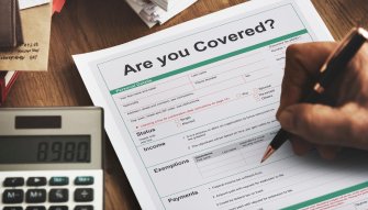 Travel insurance being signed with a calculator beside it.