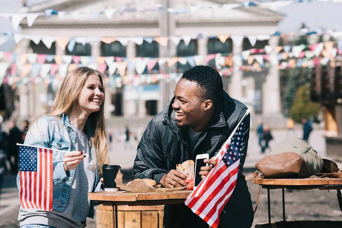 A couple outside holding an American Flag. How Americans can visit Cuba