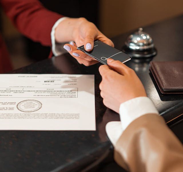 A woman handing over a tourist card to a tourist at the reception table area.