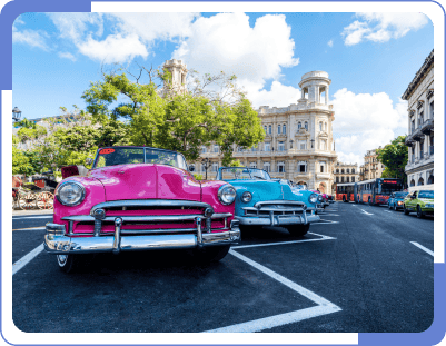 Two old model and colored cars parked in a parking area with lines
