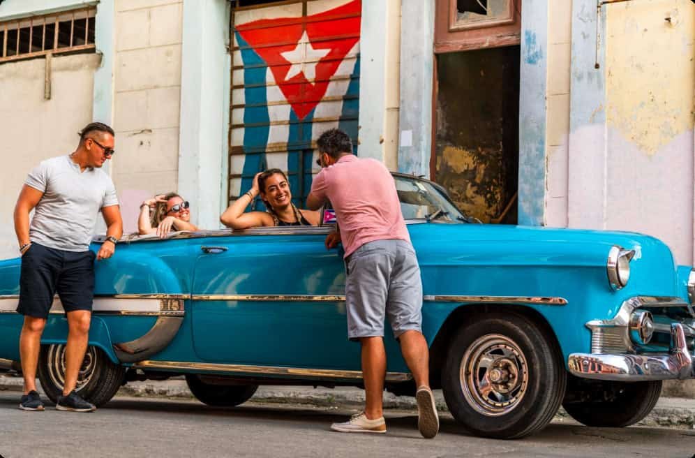 two couples enjoying their old blue Chevy in Cuba